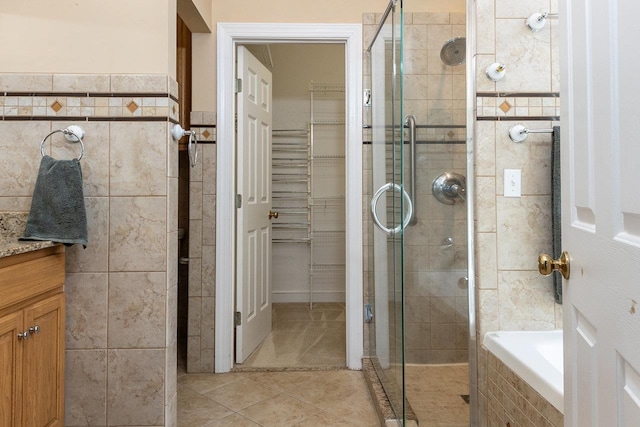 full bathroom with a shower stall, tile walls, a spacious closet, and tile patterned floors
