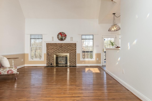 unfurnished living room with a brick fireplace, baseboards, and wood finished floors