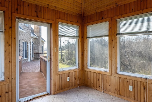 entryway featuring wooden walls, light tile patterned flooring, and baseboards
