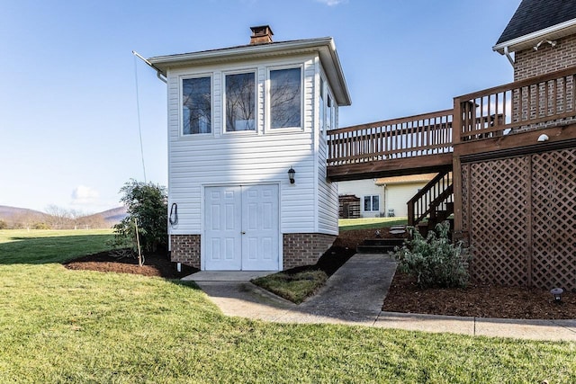 rear view of house with a lawn, a deck, stairway, and a chimney
