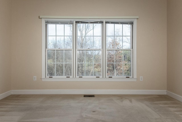carpeted spare room featuring visible vents and baseboards
