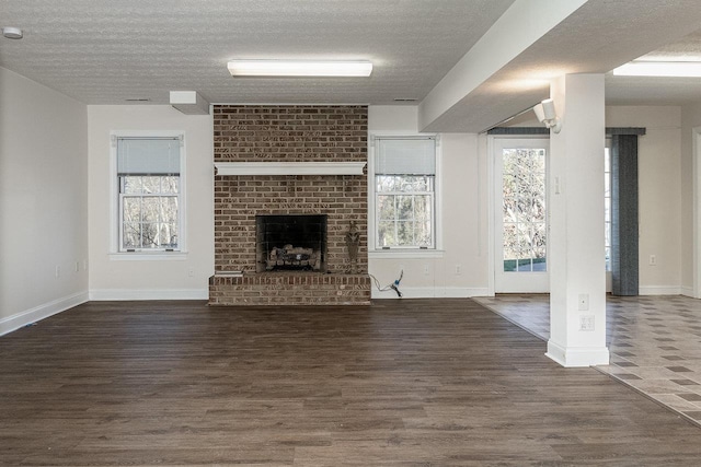 unfurnished living room featuring a textured ceiling, wood finished floors, and baseboards
