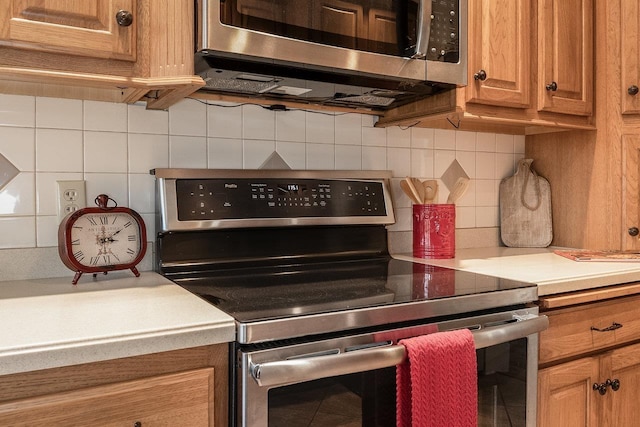 kitchen featuring light countertops, appliances with stainless steel finishes, brown cabinets, and backsplash