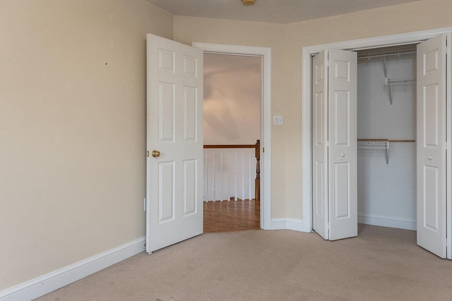 unfurnished bedroom with baseboards, carpet flooring, and a closet