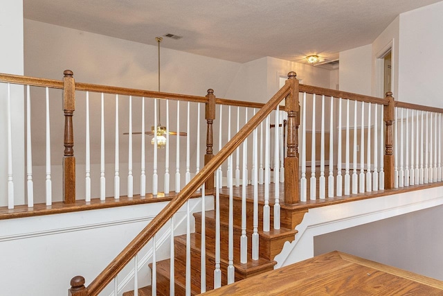 stairway featuring visible vents and a ceiling fan