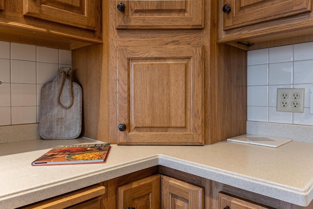 details with brown cabinetry, decorative backsplash, and light countertops