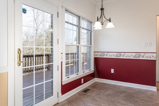 unfurnished dining area with ornamental molding, baseboards, visible vents, tile patterned floors, and a notable chandelier