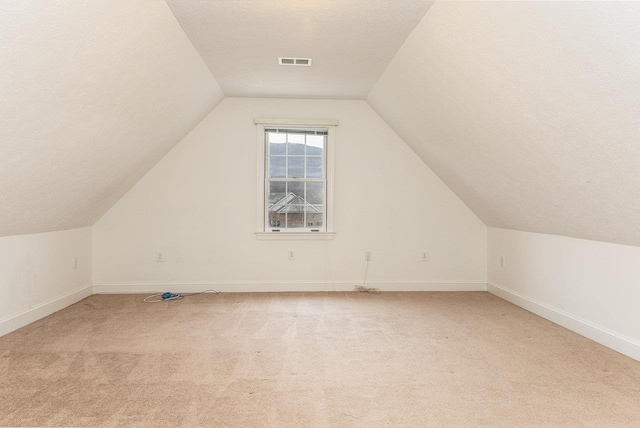 bonus room featuring lofted ceiling, light carpet, visible vents, and baseboards