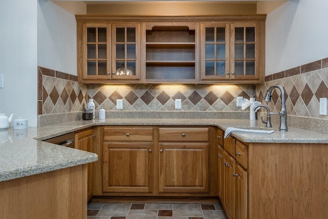 kitchen with light stone counters, glass insert cabinets, and brown cabinets