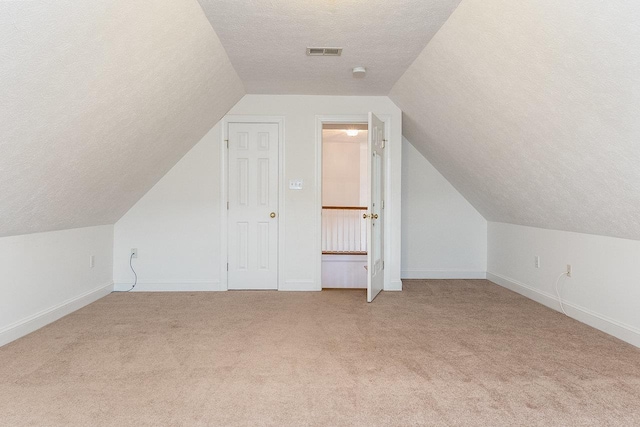 bonus room with light carpet, visible vents, a textured ceiling, and vaulted ceiling