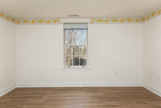empty room featuring baseboards, visible vents, and wood finished floors