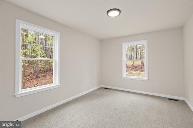 carpeted spare room featuring plenty of natural light and baseboards