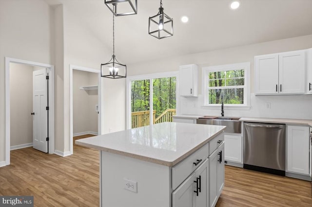 kitchen with dishwasher, a sink, a kitchen island, pendant lighting, and white cabinetry