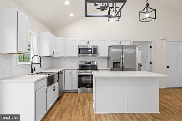 kitchen featuring appliances with stainless steel finishes, high vaulted ceiling, a center island, light countertops, and tasteful backsplash