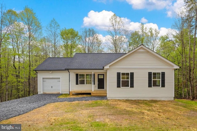 ranch-style home with a garage, gravel driveway, a shingled roof, and a front lawn