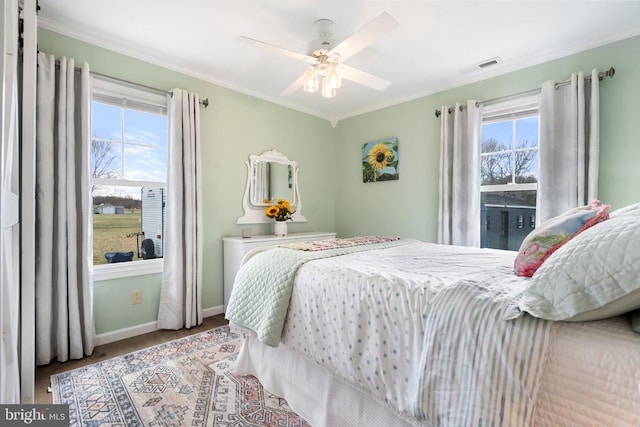 bedroom with baseboards, multiple windows, visible vents, and ornamental molding