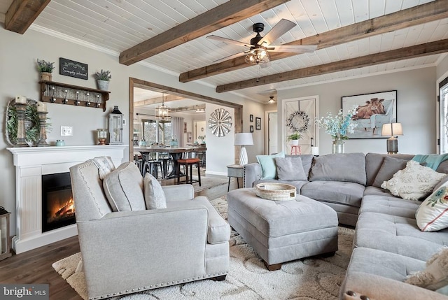 living room featuring a glass covered fireplace, beamed ceiling, wooden ceiling, and wood finished floors