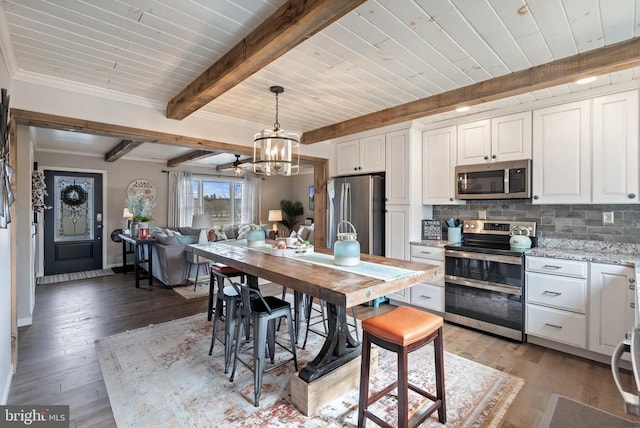 kitchen featuring light wood finished floors, decorative backsplash, appliances with stainless steel finishes, white cabinetry, and beam ceiling