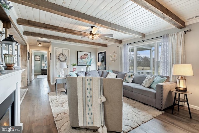 living room with baseboards, visible vents, hardwood / wood-style flooring, and a ceiling fan