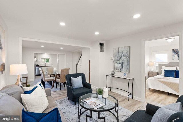 living area featuring stairs, light wood finished floors, baseboards, and recessed lighting