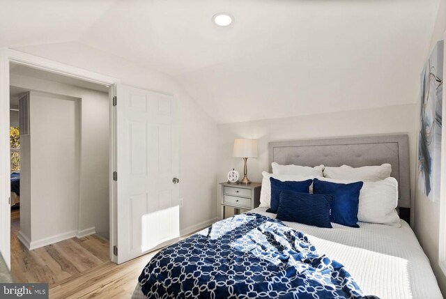 bedroom featuring lofted ceiling, radiator, baseboards, and wood finished floors