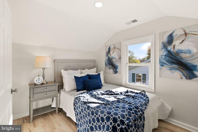 bedroom featuring lofted ceiling, wood finished floors, visible vents, and baseboards