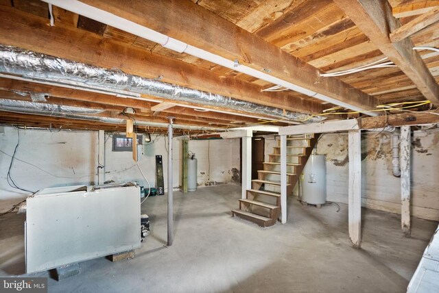 unfinished basement featuring water heater, stairway, and gas water heater