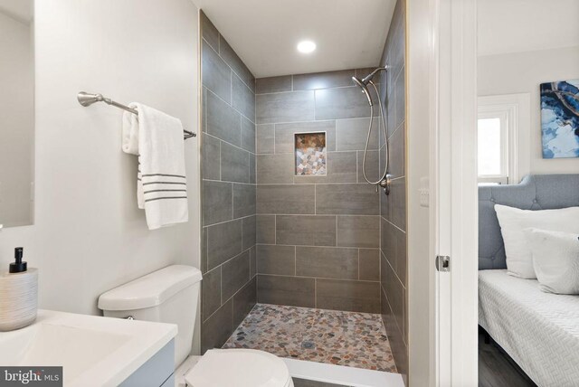 full bath with tiled shower, vanity, and toilet