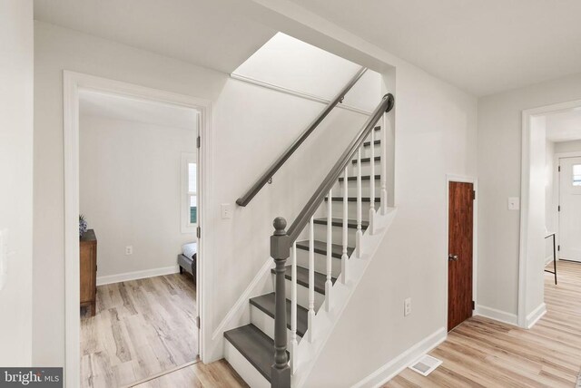 stairway with wood finished floors, visible vents, and baseboards