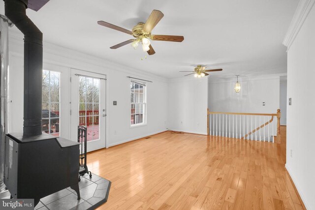 5519 Bazzanella Dr, Mineral, VA 23117 - unfurnished living room with a wood stove, crown molding, a ceiling fan, light wood-style flooring, and baseboards