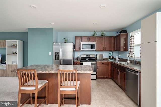 kitchen with appliances with stainless steel finishes, a sink, a center island, and a breakfast bar