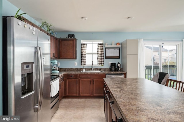 kitchen featuring appliances with stainless steel finishes, a sink, and dark countertops