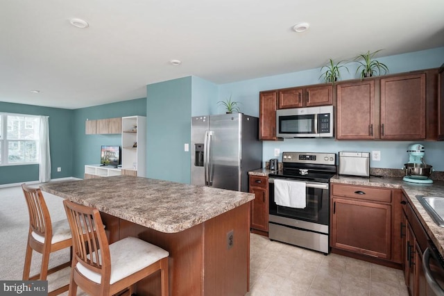 kitchen featuring stainless steel appliances, a breakfast bar, a kitchen island, and a sink