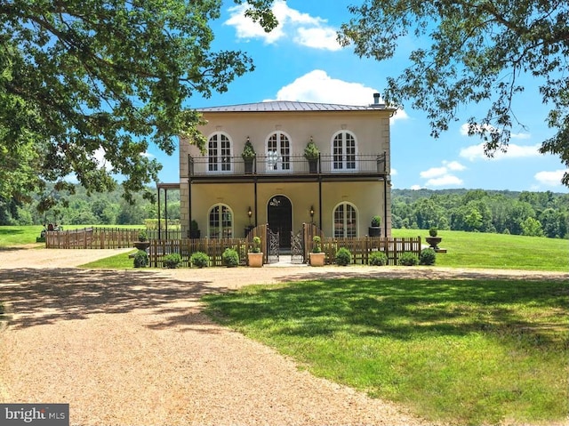 8833 Wales Rd N, Warrenton, VA 20186 - mediterranean / spanish-style home with a balcony, a fenced front yard, stucco siding, a standing seam roof, and a metal roof