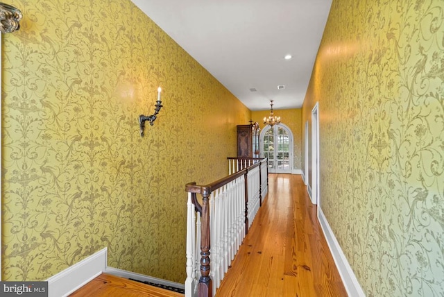 8833 Wales Rd N, Warrenton, VA 20186 - hallway featuring wallpapered walls, wood finished floors, a chandelier, and an upstairs landing