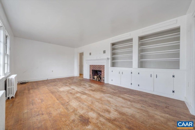 2420 James River Rd, Esmont, VA 22937 - unfurnished living room featuring baseboards, radiator, built in shelves, wood finished floors, and a fireplace