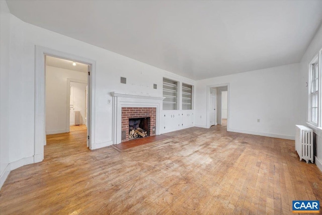 2420 James River Rd, Esmont, VA 22937 - unfurnished living room featuring radiator, hardwood / wood-style floors, a brick fireplace, and built in shelves