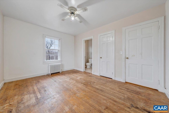 2420 James River Rd, Esmont, VA 22937 - unfurnished bedroom featuring a ceiling fan, baseboards, radiator, connected bathroom, and hardwood / wood-style flooring