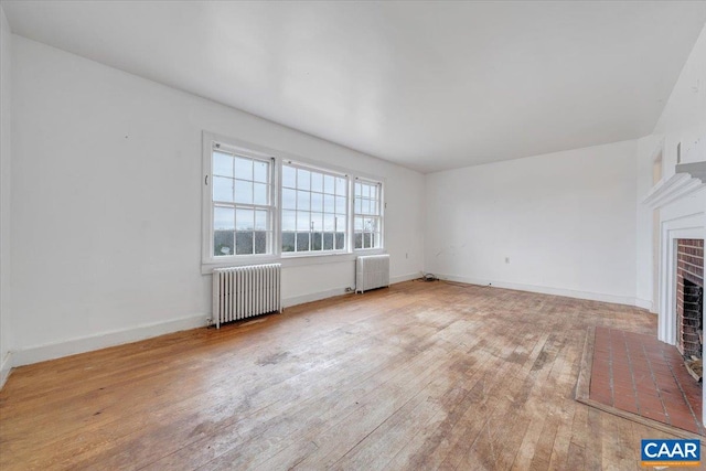 2420 James River Rd, Esmont, VA 22937 - unfurnished living room featuring radiator, baseboards, a brick fireplace, and hardwood / wood-style flooring
