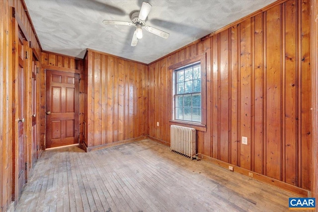 2420 James River Rd, Esmont, VA 22937 - unfurnished room with baseboards, radiator, ceiling fan, wood walls, and hardwood / wood-style floors