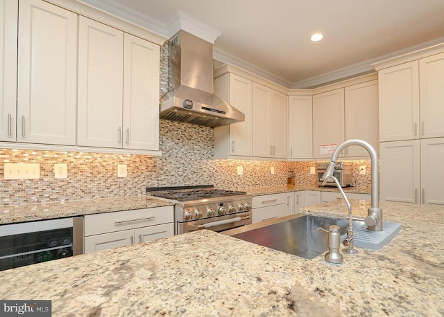  - kitchen with wall chimney exhaust hood, high end range, a sink, crown molding, and light stone countertops