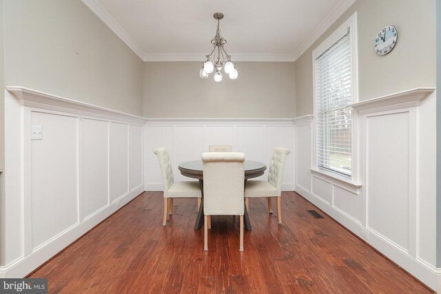  - dining room with a decorative wall, a chandelier, plenty of natural light, wood finished floors, and crown molding