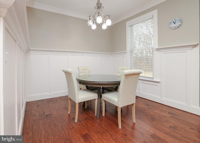 - dining area featuring a decorative wall, wood finished floors, a chandelier, ornamental molding, and a wainscoted wall