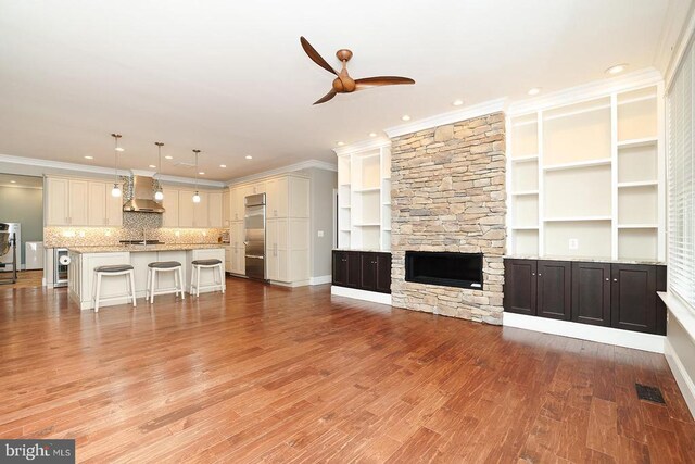  - unfurnished living room featuring ceiling fan, ornamental molding, recessed lighting, light wood-style flooring, and a fireplace