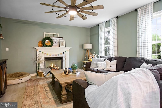 living area featuring a ceiling fan, plenty of natural light, light wood-style flooring, and a premium fireplace
