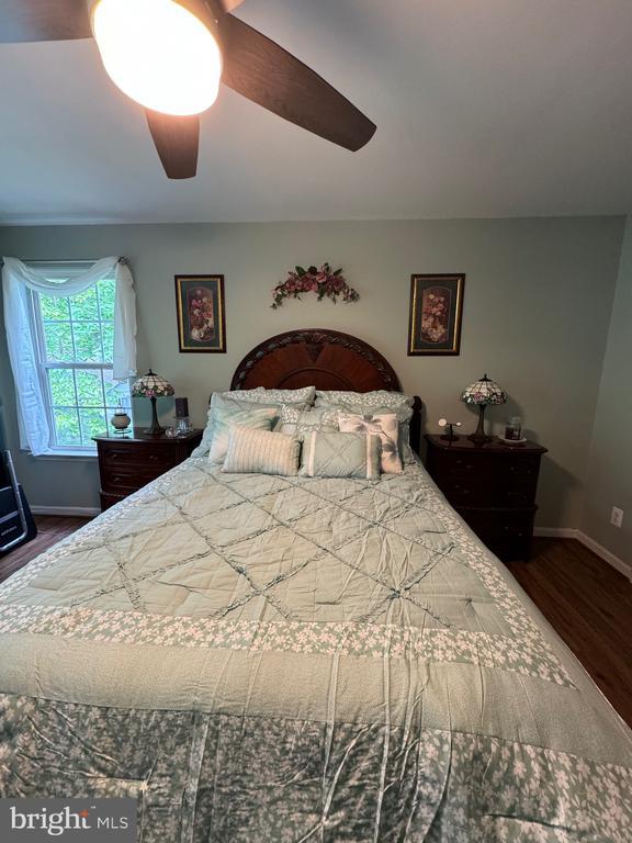 bedroom featuring wood finished floors, baseboards, and ceiling fan