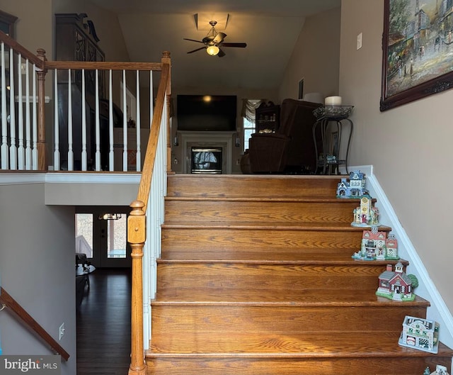 stairway featuring ceiling fan, lofted ceiling, and wood finished floors