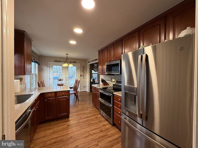 kitchen with appliances with stainless steel finishes, light wood-style floors, decorative backsplash, recessed lighting, and a peninsula