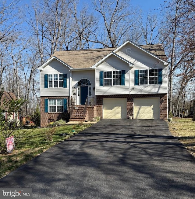 raised ranch with brick siding, asphalt driveway, and a garage