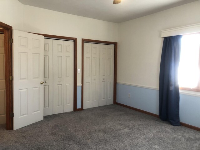 unfurnished bedroom with multiple closets, ceiling fan, and carpet flooring